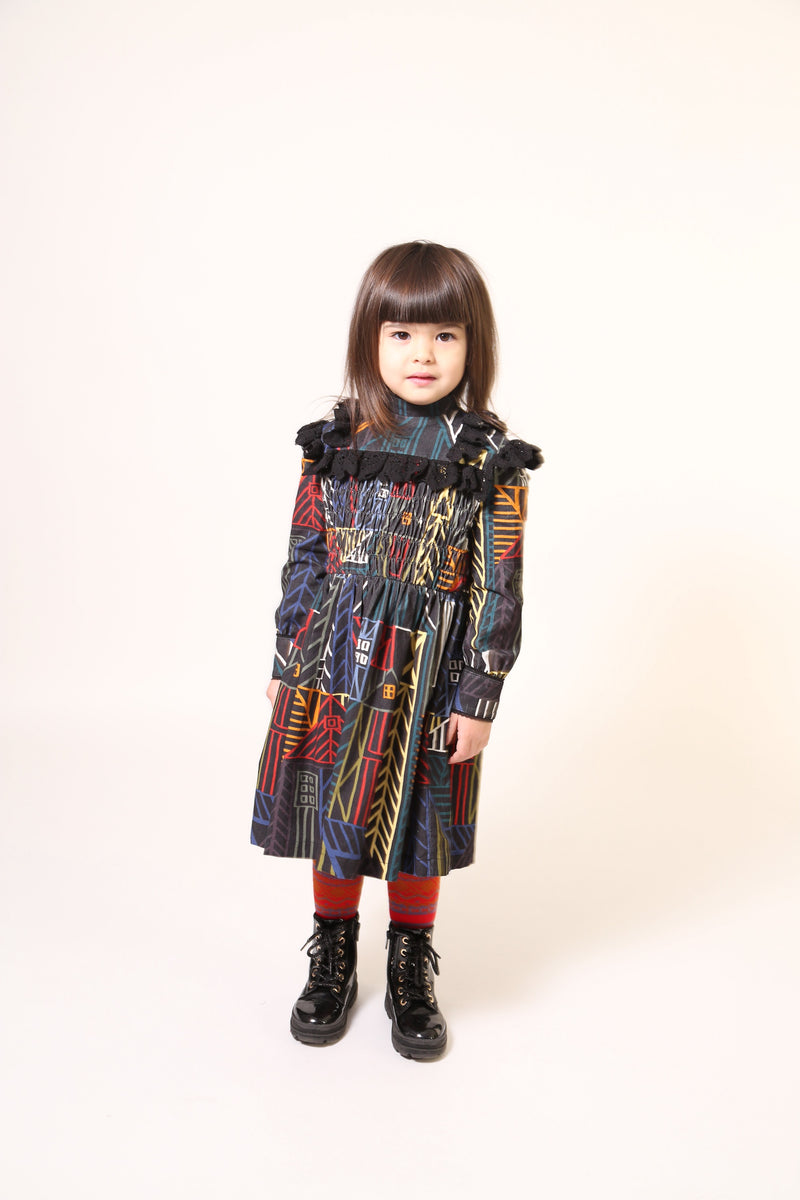 Girl wearing a flared long sleeve frock in this season's Normanz print on soft corduroy features black color smocking at the bodice, Multicolour, Tia Cibani.