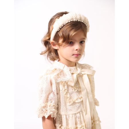 Girl wearing a White padded thick base headband covered in taffeta with pleated lace and hand-stitched pearls at the front, Tia Cibani.