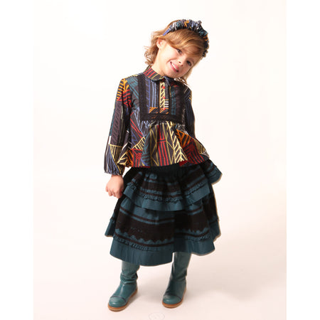 Girl wearing a tealength two-tiered taffeta skirt with elasticized smocking at the waistband, embroidered lace trim, and ribbon at each tier. Unlined for lightweight feel. Colour: Celtic, Tia Cibani.