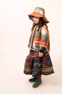 Girl wearing a rainbow printed voluminous skirt features diamond harlequin pattern tufting and padded design, Tia Cibani.