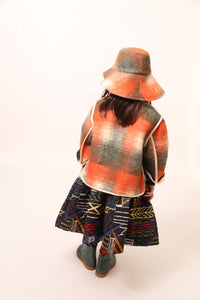 Girl wearing a rainbow printed voluminous skirt features diamond harlequin pattern tufting and padded design, Tia Cibani.