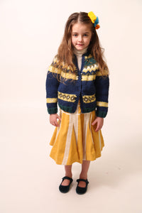 Girl wearing a long-sleeve cardigan in Yarn fabric, central button closure, predominantly blue with yellow and green accents, by Tia Cibani.