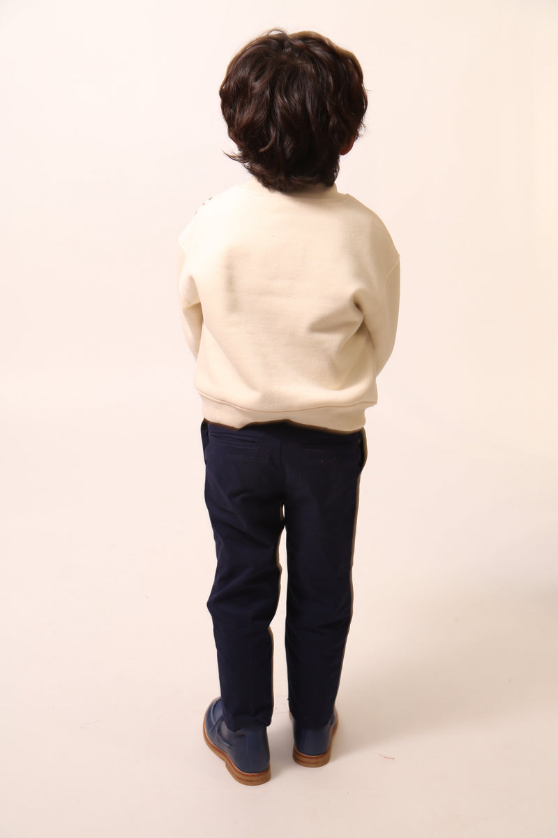 Boy wearing Sueded Fleece jersey pullover for boys, featuring long sleeves, tonal jersey ribbing at neckline, hem, and cuffs for comfort and style. Colorful asymmetric screen print at shoulder. Taffeta pocket detail at left chest for treasures. Dropped shoulders, relaxed fit. White, Tia Cibani.