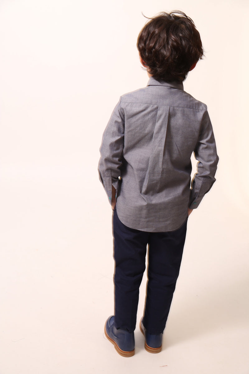 Boy wearing a western-inspired take on classic boy's button-up with scoop high-low hem for modern twist. Built-in vest with two-toned embroidery design and textured ribbons at overlay. Snap closure at center front for easy dressing. Perfect for any occasion, from family gatherings to formal events. Cotton. Blue, Tia Cibani. 