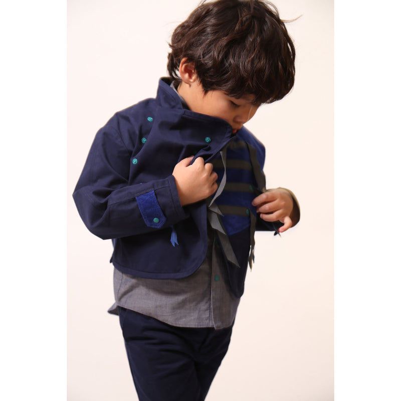 Bold and stylish Malok Military Jacket for boys, inspired by traditional military dress. Patchworked with cotton twill and velvet accents. Features zip welt pockets, yoke at back, snap tabs at sleeves, and double-breasted snap closure for comfort and charm. Relaxed box fit for easy layering. Textured structured ribbon details on front and sleeves with free-hanging tassels for contemporary flair. Scoop hem, stand-up collar. Perfect with Malok Slim Fit Trousers. Blue, Tia Cibani.