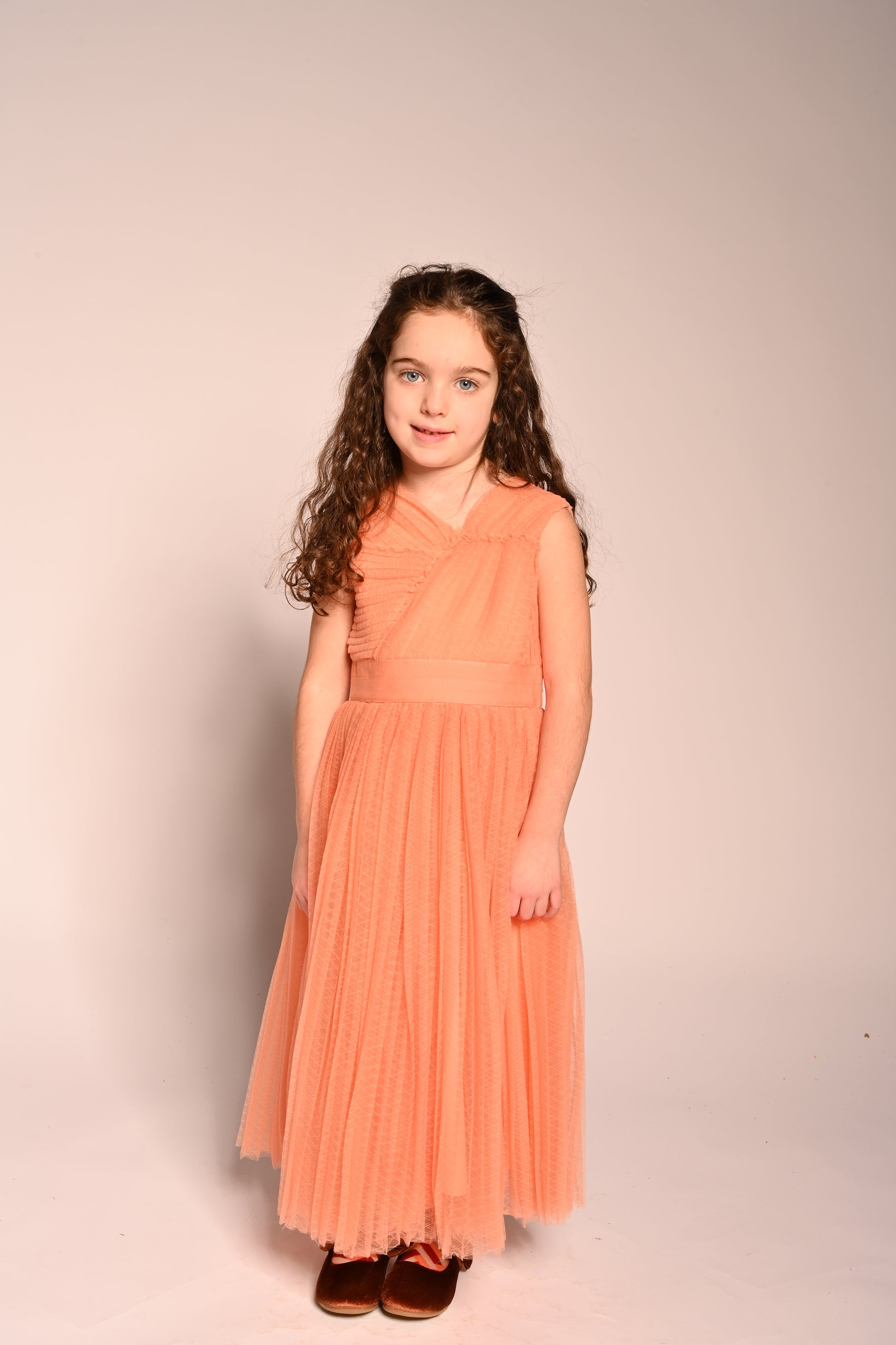 girl wearing orange pink tulle sleeveless gown length dress