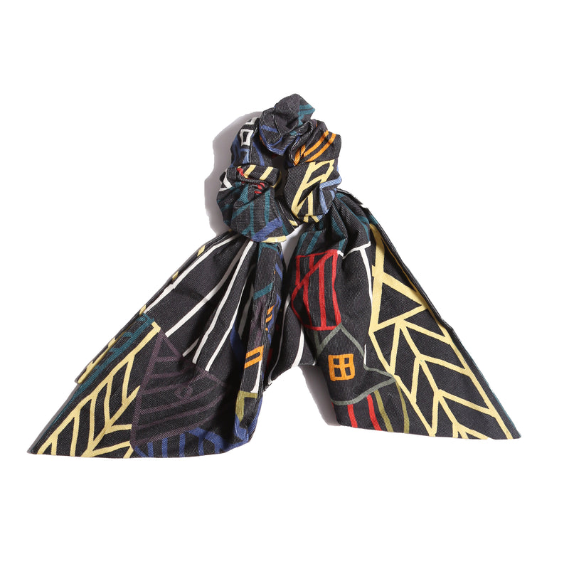 Scrunchie designed in Rainbow Normanz print, adorned with scarf-like tassels for a versatile look. Can be tied in a bow at the back or left free, by Tia Cibani.