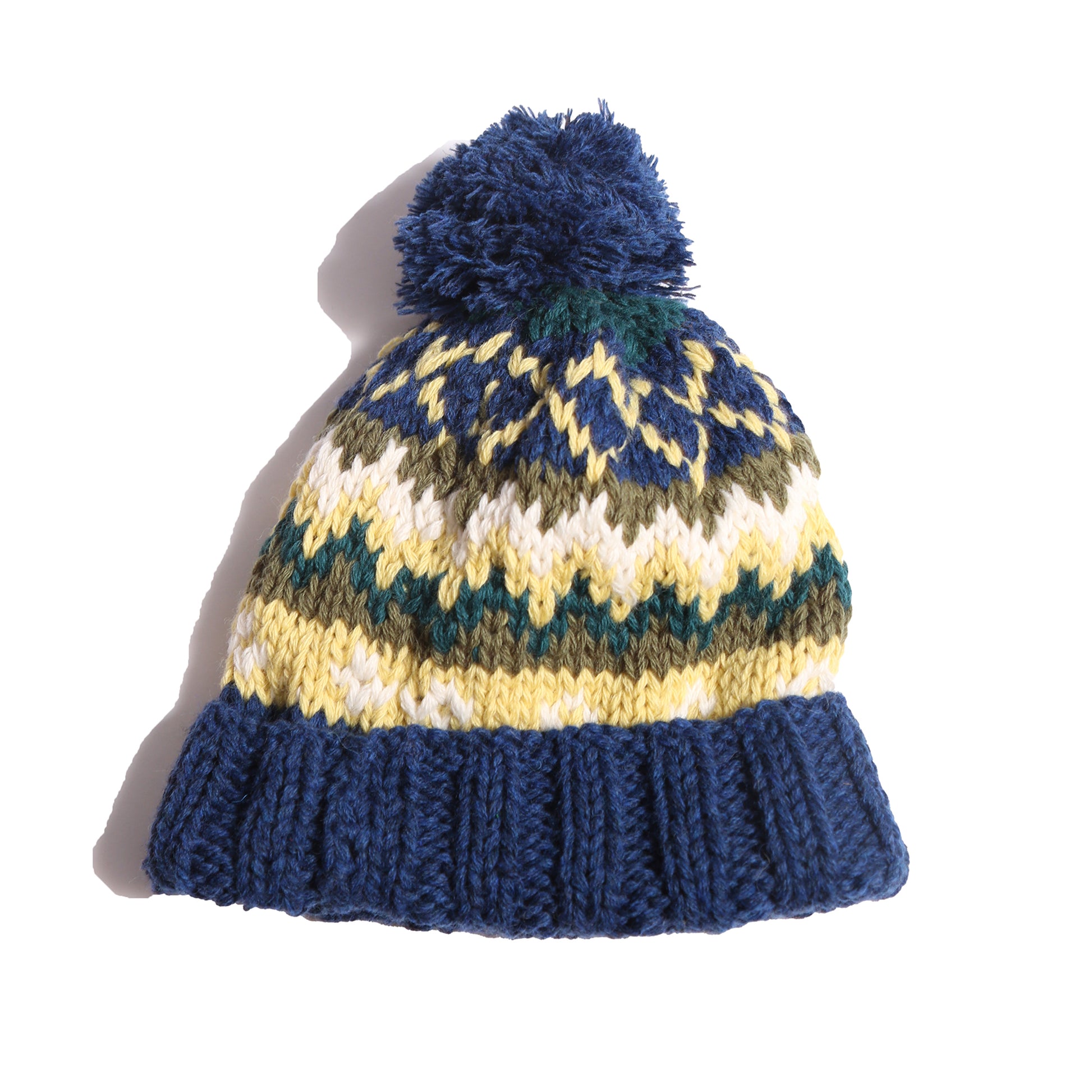 Hand-knitted toque in 100% wool with multi-colored fair isle pattern, large pom pom at top, and ribbing at bottom for easy folding. Colour: Blue and yellow, Tia Cibani.