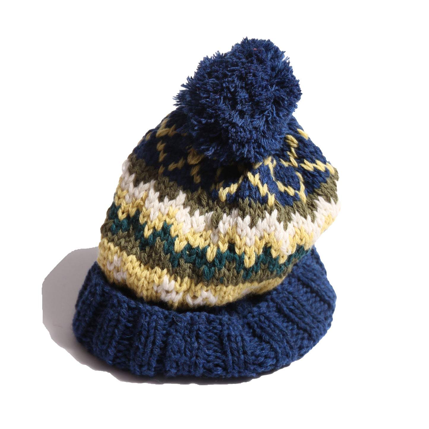 Hand-knitted toque in 100% wool with multi-colored fair isle pattern, large pom pom at top, and ribbing at bottom for easy folding. Colour: Blue and yellow, Tia Cibani.