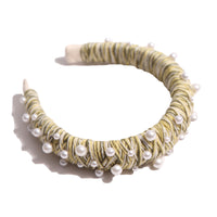 Headband covered in mustard yellow and white thread with various pearls attached, by Tia Cibani.