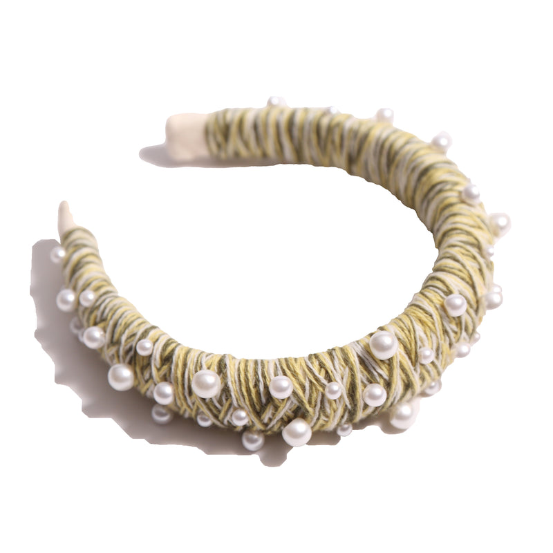 Headband covered in mustard yellow and white thread with various pearls attached, by Tia Cibani.