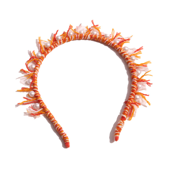 Headband wrapped in multi-colored, predominantly orange, wool yarn, with fringing at the crown and hand-stitched pearls at the top, by Tia Cibani.