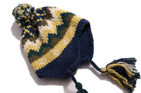 Cozy and playful toque style hat with multi-color tassels and pom pom at the top for a fun pop of color. Features ear flaps for extra warmth, hand-knitted with charming colorful fair isle pattern. Made of 100% Wool. Wear with this season's fair isle sweaters or outerwear pieces. Blue and yellow, Tia Cibani.