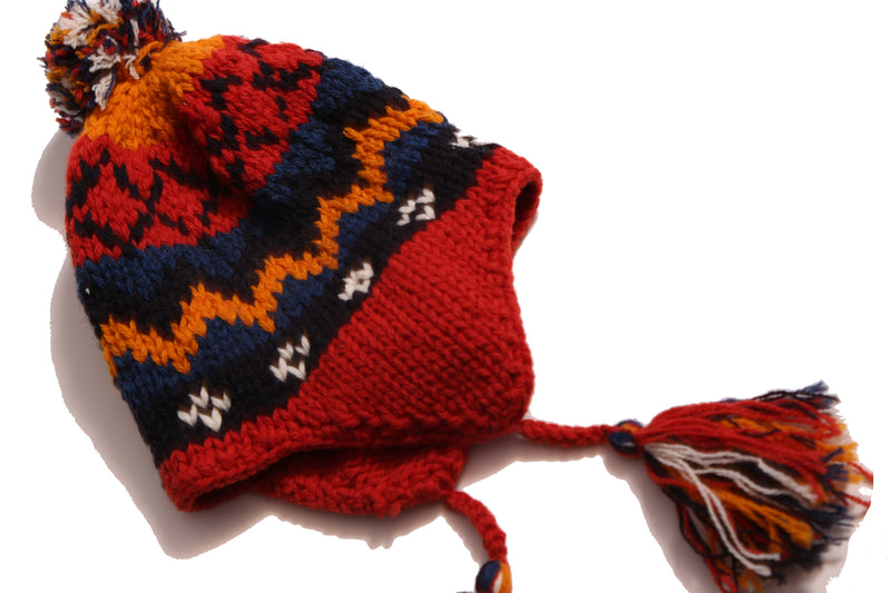 Cozy and playful toque style hat with multi-color tassels and pom pom at the top for a fun pop of color. Features ear flaps for extra warmth, hand-knitted with charming colorful fair isle pattern. Made of 100% Wool. Wear with this season's fair isle sweaters or outerwear pieces. Blue and rouge, Tia Cibani.