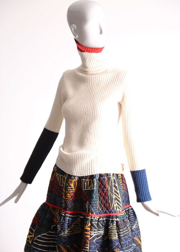 Slim fit, ribbed Felted Wool Yarn turtleneck with multi-color contrasting patchwork at sleeves. Bold spin on classic basic for mom. High-quality knit staple for fall and winter seasons. Wool, white. By Tia Cibani.