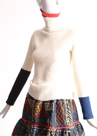 Slim fit, ribbed Felted Wool Yarn turtleneck with multi-color contrasting patchwork at sleeves. Bold spin on classic basic for mom. High-quality knit staple for fall and winter seasons. Wool, white. By Tia Cibani.