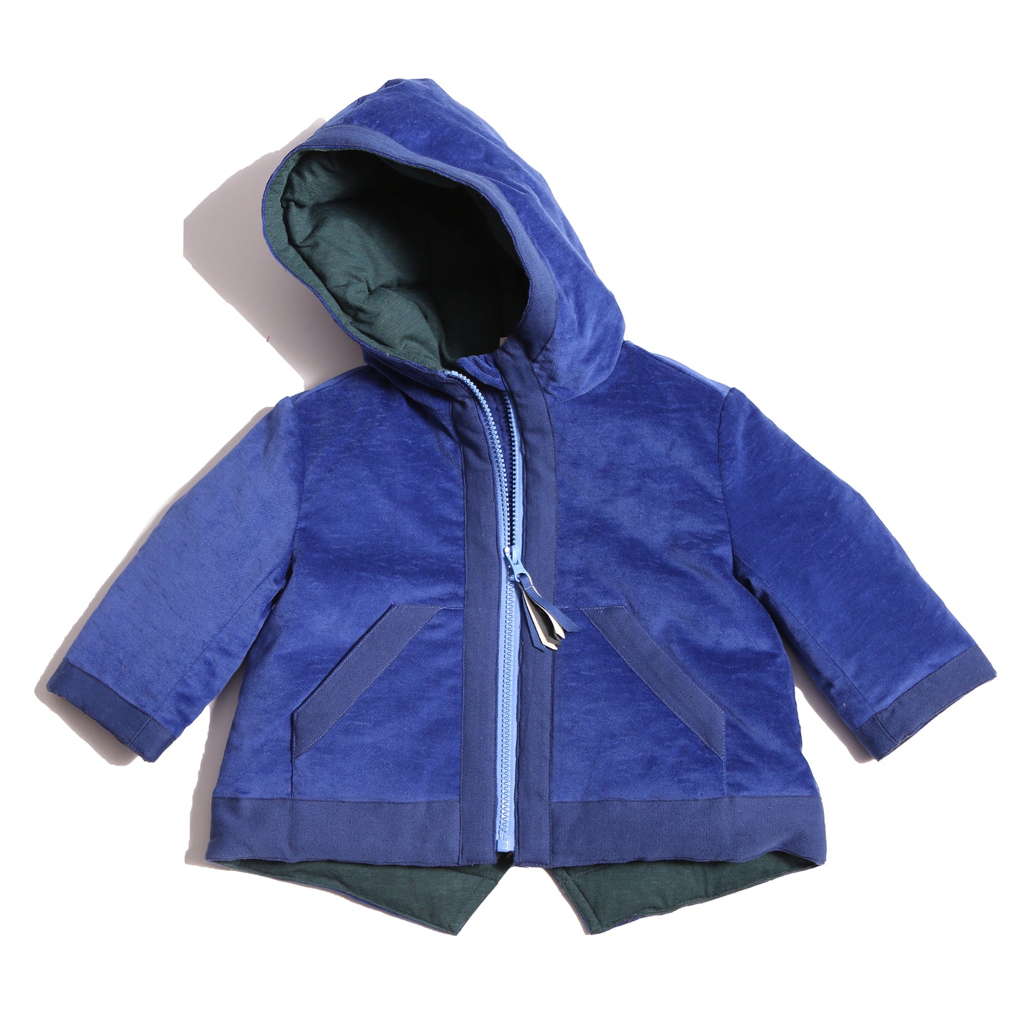 Baby coat made from Blue Breton Tarp Velvet, featuring down filling, an attached hood, slanted ribbon welt pockets, a V cut-out vent at the back hemline, and a center front zipper with a multi-colored ribbon pully for added flair. Lined with soft jersey at the body and nylon lining in the sleeves, by Tia Cibani.