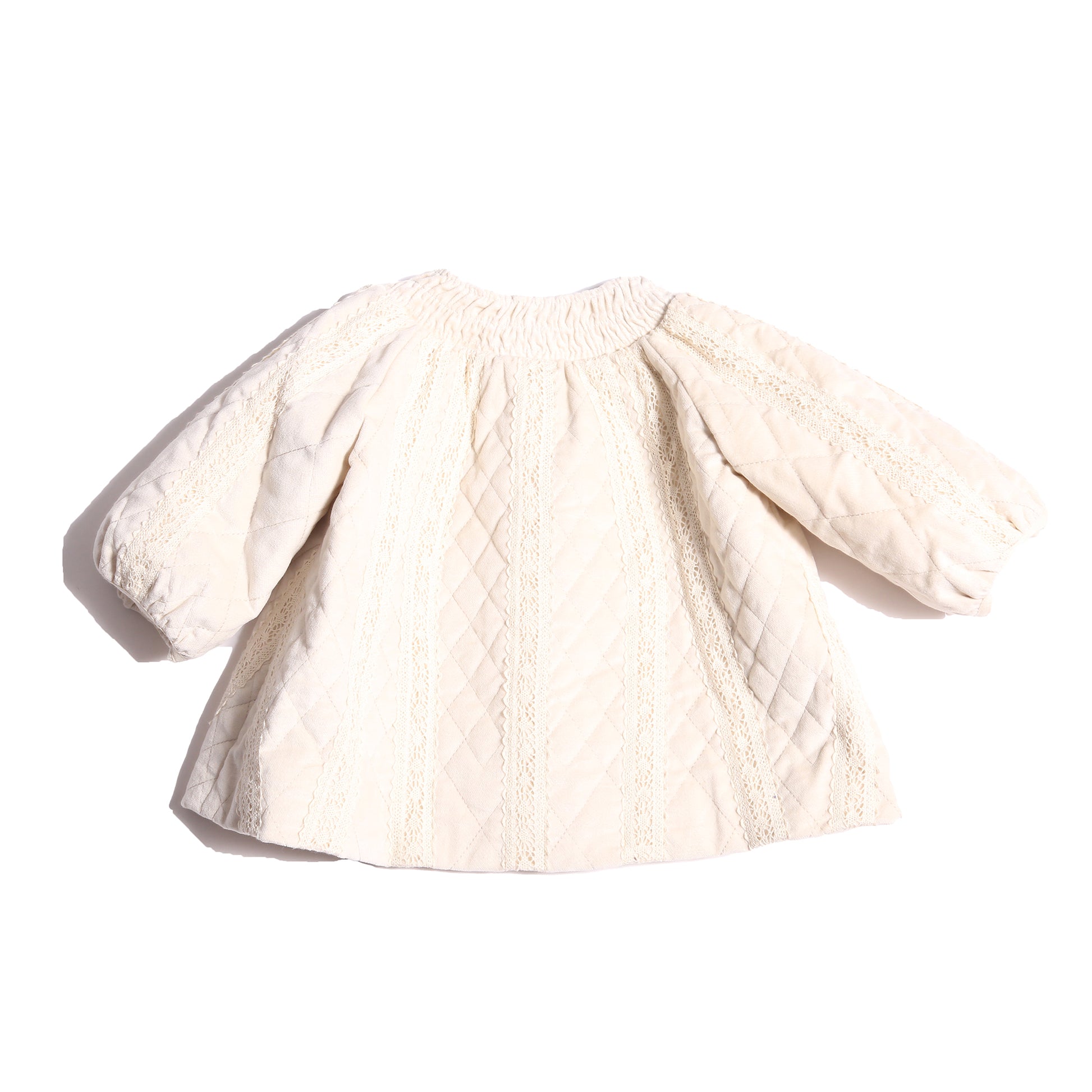 Adorable baby girl jacket in Opal color, featuring lace trim appliqué throughout and tonal intricate smocking at the neckline. Lightly padded for warmth and comfort, with cinched sleeve cuffs and minimal ribbons at the center front for a decorative touch. Lined in soft cotton striped shirting at the body and cire at the sleeves. Perfect for chilly days, by Tia Cibani. Back View.