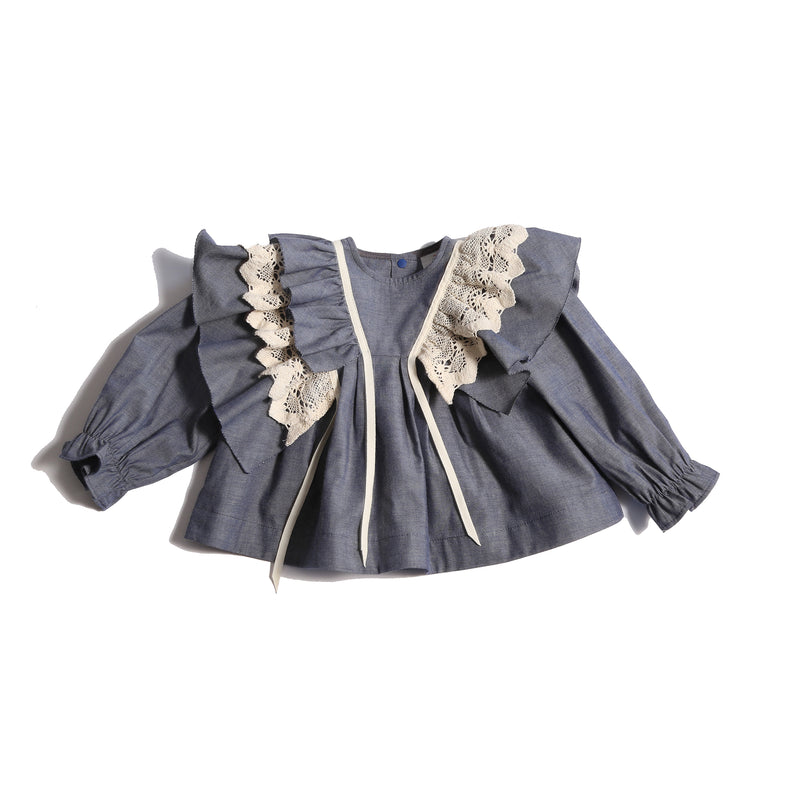 Baby blouse in 100% Cotton with 3-dimensional lace trim ruffling at shoulders, self-ruffles, and decorative ribbon. Snaps at back, cinched long sleeves for snug fit. Unlined for lightweight feel. Colour: Blue, Tia Cibani.