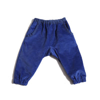 Wolf Baby Track Pants in Breton Tarp Velvet, featuring gentle elastic waistband for relaxed fit. Front slant pockets, cotton canvas ribbon trim, and back patch pocket with snap button detail. Drop rise design for comfort on the go. Pair with Baby Malok Military Jacket or Baby Malok Padded Vest for a cute look. Blue, Tia Cibani.