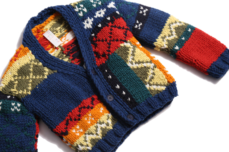  Colorful fair isle cardigan in a patchwork design, blending various fair isle patterns with solid colors of Felt Wool Yarn. Features a relaxed fit with faux horn buttons at the center front, ideal for layering over basic knits. Made from 100% Wool. Color: Multicolor. By Tia Cibani.