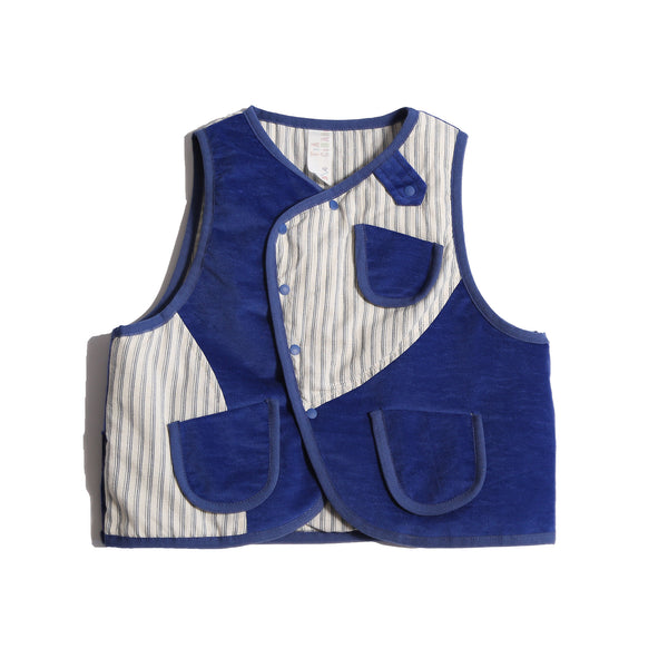 Versatile padded patchwork vest for boys, combining style and comfort with easy box fit for layering. Features binding tape at edges, patch pockets for treasures, and snap button closure at center front flap. Fully faced in cotton striped shirting, patchworked with structured velvet exterior for added fun. Great for formal and casual occasions. Pair with classic boy's button-ups and Breton Slim Fit Trousers for refined look. Blue and white, Tia Cibani.