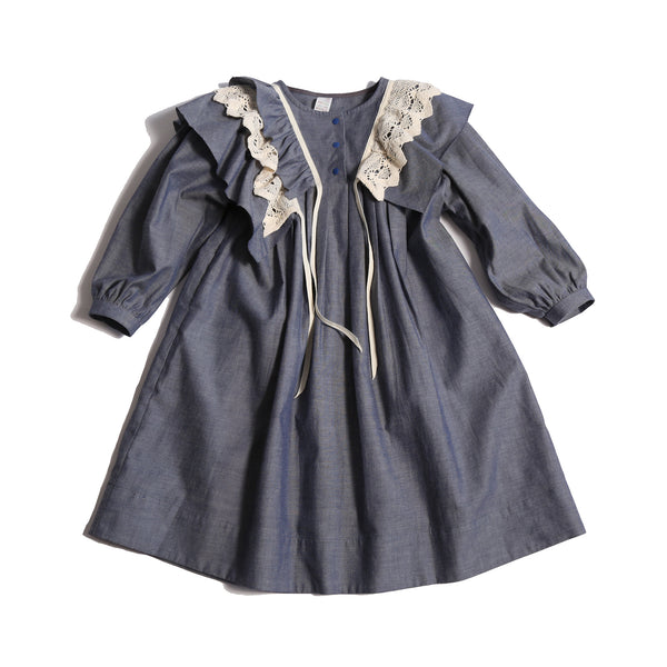 Voluminous dress in unlined Chambray Cotton Shirting with 3-D self ruffles at shoulders and delicate lace ruffles overlay. Decorative ribbons from ruffles. Long cinched sleeves, tealength silhouette, henley snap placket at center front neckline. Colour: Blue, Tia Cibani.