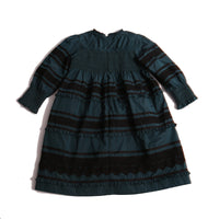 Tealength frock in luxurious Taffeta with elasticized smocking at bust and cuffs, tiers of ribbons and lace trim, invisible zipper at back, long cinched sleeves, and square ruffled neckline. Unlined for lightweight feel. Colour: Celtic and Black, Tia Cibani.