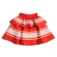 Tealength two-tiered taffeta skirt with elasticized smocking at the waistband, embroidered lace trim, and ribbon at each tier. Unlined for lightweight feel. Colour: Rouge and White, Tia Cibani.