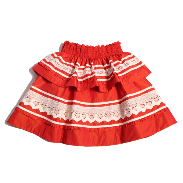 Tealength two-tiered taffeta skirt with elasticized smocking at the waistband, embroidered lace trim, and ribbon at each tier. Unlined for lightweight feel. Colour: Rouge and White, Tia Cibani.