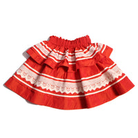 Tealength two-tiered taffeta skirt with elasticized smocking at the waistband, embroidered lace trim, and ribbon at each tier. Unlined for lightweight feel. Colour: Rouge and White, Tia Cibani.