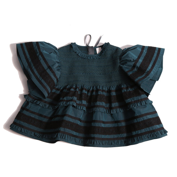 Top in luxurious Taffeta with elasticized smocking at neckline, ruffle detail, and embroidered lace trim and ribbon at body and flutter sleeves. Tonal ribbon ties at the back of the neck. Unlined for lightweight feel. Colour: Celtic and black, Tia Cibani.