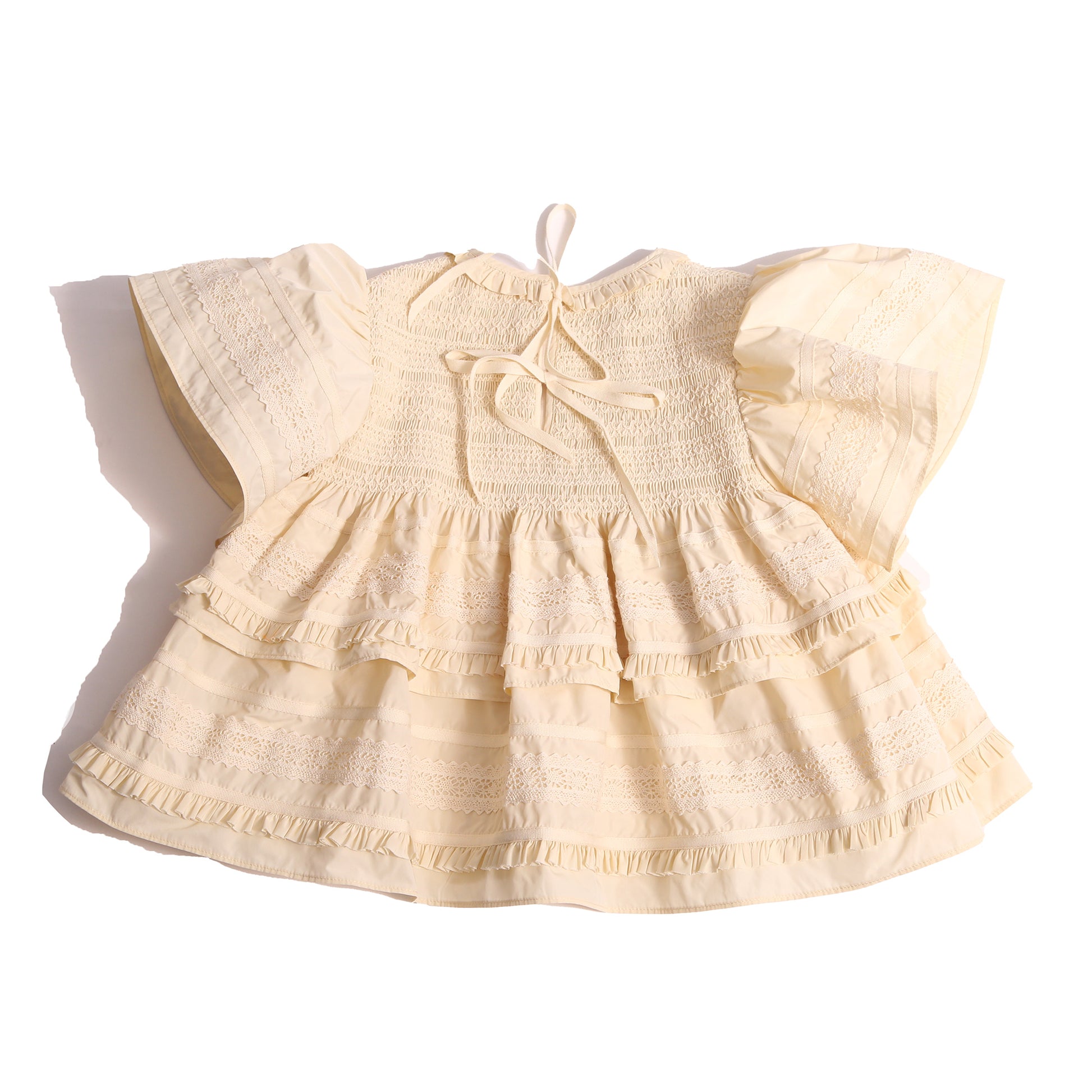 Top in luxurious Taffeta with elasticized smocking at neckline, ruffle detail, and embroidered lace trim and ribbon at body and flutter sleeves. Tonal ribbon ties at the back of the neck. Unlined for lightweight feel. Colour: White, Tia Cibani.