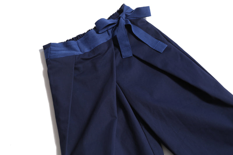 Deep pleated trousers designed for comfort and style, featuring an easy elastic waistband with ribbon tie detailing for a charming bow at the side waist. Crafted in comfortable Chamois Cotton Twill, unlined for lightweight feel, perfect for everyday wear. Complete with slant pockets at side seams. Pair with Gwenn Collared Topper for a complete look. Blue, Tia Cibani.