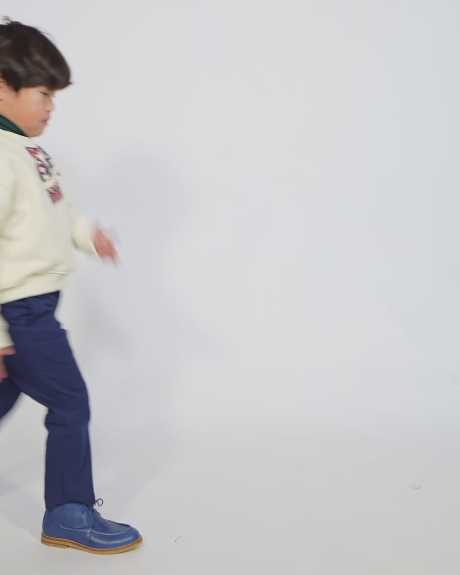 Boy wearing Sueded Fleece jersey pullover for boys, featuring long sleeves, tonal jersey ribbing at neckline, hem, and cuffs for comfort and style. Colorful asymmetric screen print at shoulder. Taffeta pocket detail at left chest for treasures. Dropped shoulders, relaxed fit. White, Tia Cibani.