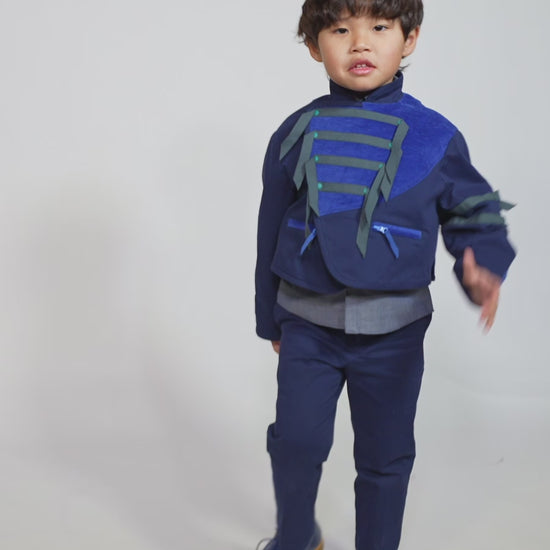 Boy wearing a western-inspired take on classic boy's button-up with scoop high-low hem for modern twist. Built-in vest with two-toned embroidery design and textured ribbons at overlay. Snap closure at center front for easy dressing. Perfect for any occasion, from family gatherings to formal events. Cotton. Blue, Tia Cibani. 