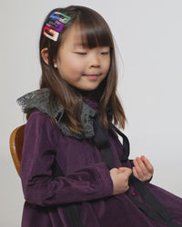 Girl wearing a set of 3 pairs, 6 hair clips featuring multi-color rope and embroidery thread combinations. Each pair unique, wear individually or all together for flair. Rainbow, Tia Cibani.